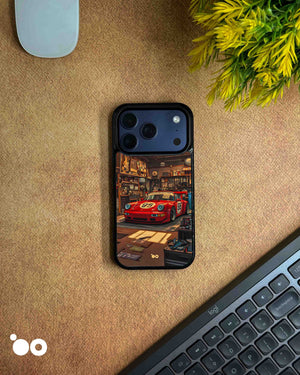 Porsche 911 iPhone case featuring a vintage red racing Porsche with number 95, parked inside a detailed retro garage with warm lighting, workshop tools and automotive memorabilia.